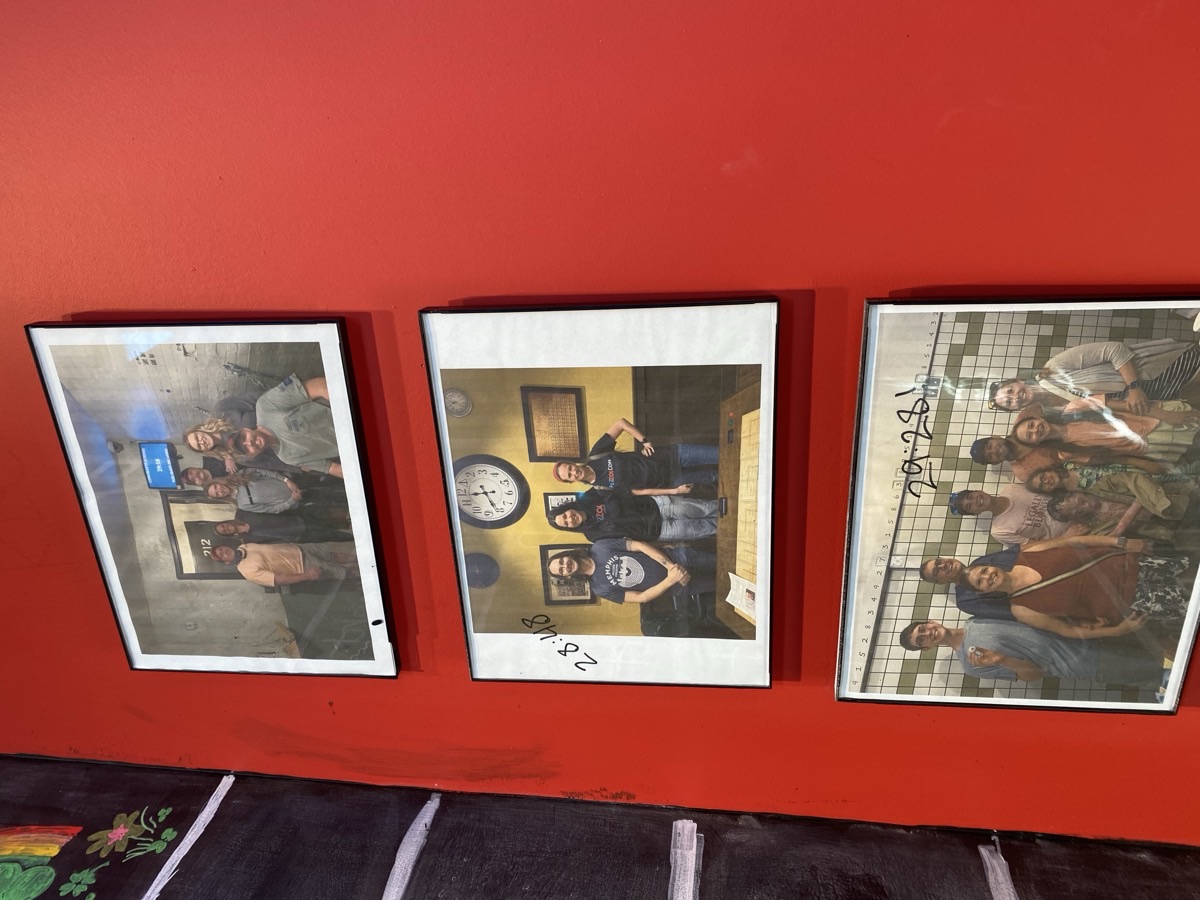 Framed photos of record-holding escape room teams displayed on the wall at Escape Experience Chattanooga